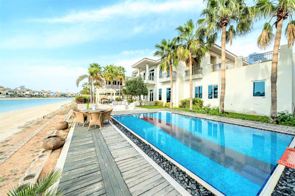 a house on the beach with a swimming pool and palm trees at Ultimate Luxury sea front villa with private pool Palm Jumeirah in Dubai