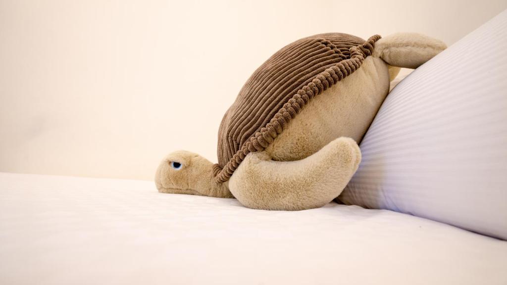 a teddy bear is laying on a bed at It's Mine Hostel in Taitung City