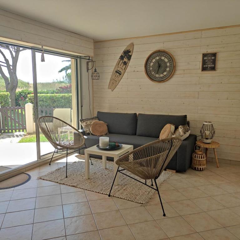 uma sala de estar com um sofá e duas cadeiras em LES CAPITELLES - Accès direct à la plage depuis le jardin em Saint-Cyprien