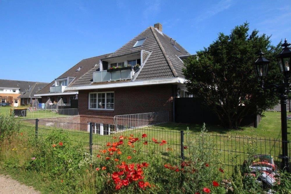 a house with a fence and flowers in front of it at Seaside-Amrum-10 in Norddorf