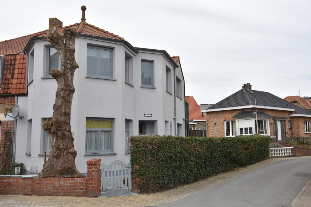 a white house with a tree in front of it at villa alice in Koksijde