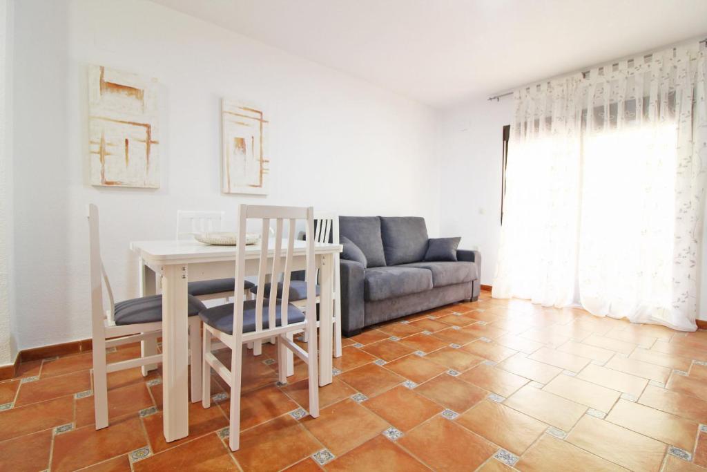 ein Wohnzimmer mit einem Tisch, Stühlen und einem Sofa in der Unterkunft Global Properties, El Coquetón - Bonito y tranquilo apartamento en Canet playa in Canet d'en Berenguer