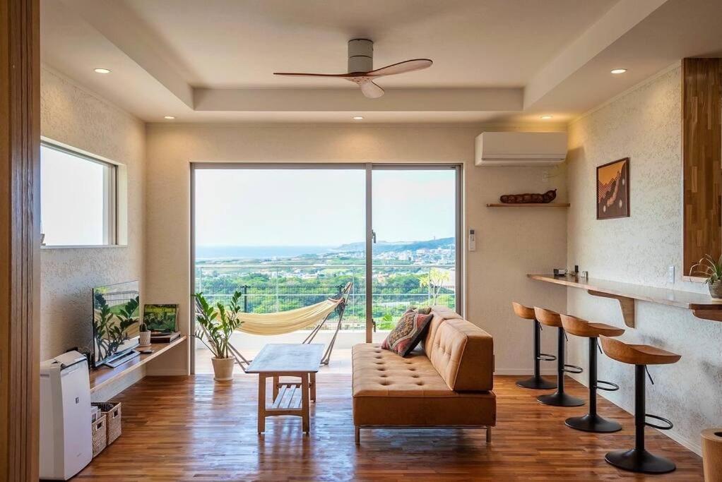 a living room with a couch and a large window at villa modama in Nanjo