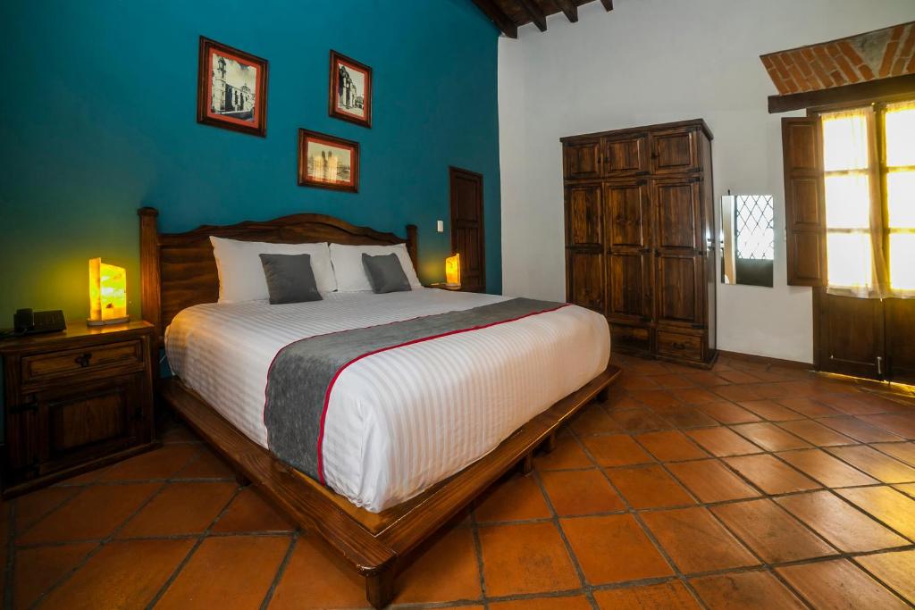 1 dormitorio con 1 cama grande y pared azul en Collection O Al otro lado del rio, Puebla en Puebla