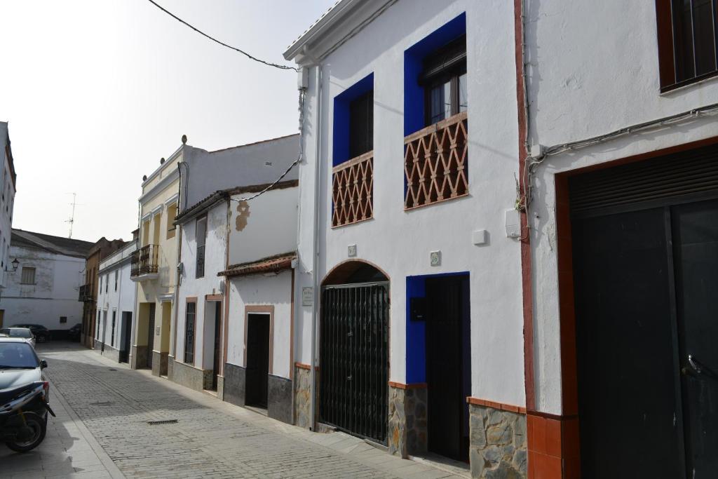 a row of buildings with blue doors on a street at El Regocijo in Oliva de la Frontera