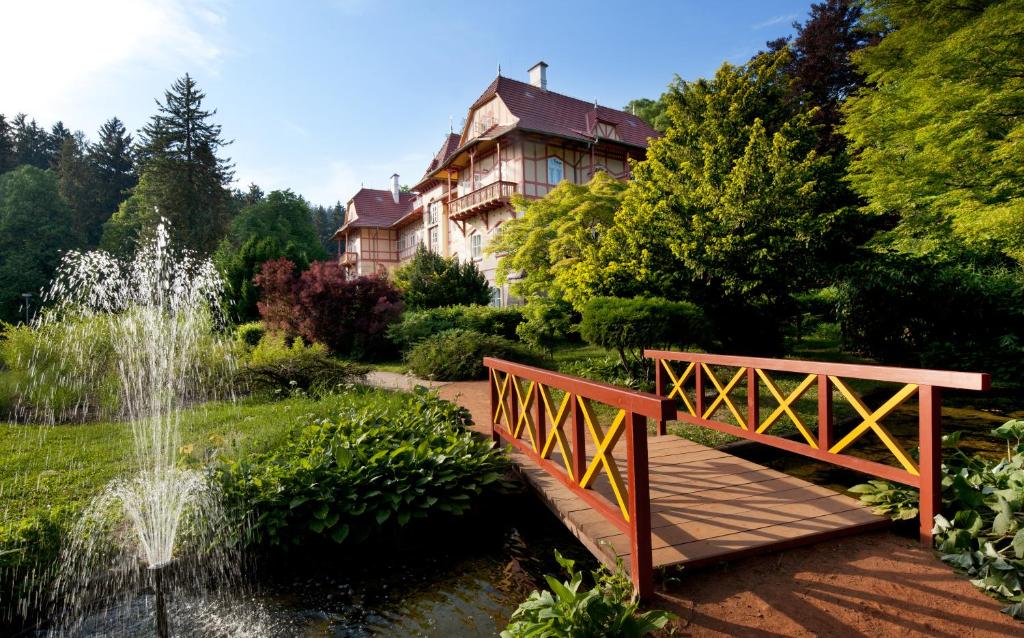 a bridge over a pond in a garden with a house at Jestřabí in Luhačovice