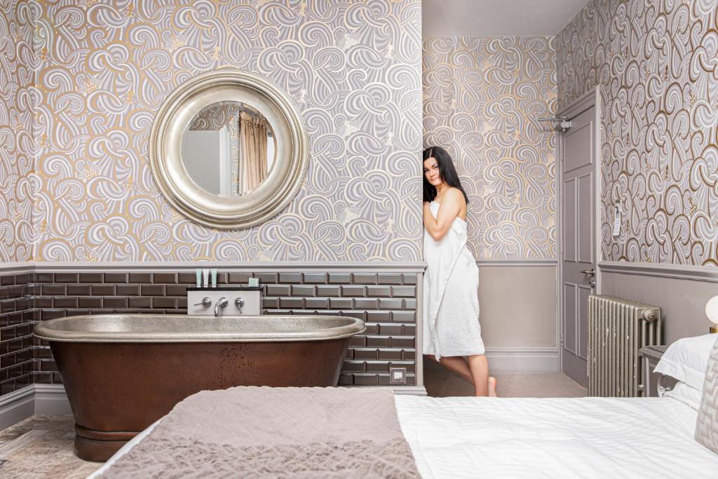 a woman standing in a bathroom next to a tub at Escape Boutique B&B in Llandudno