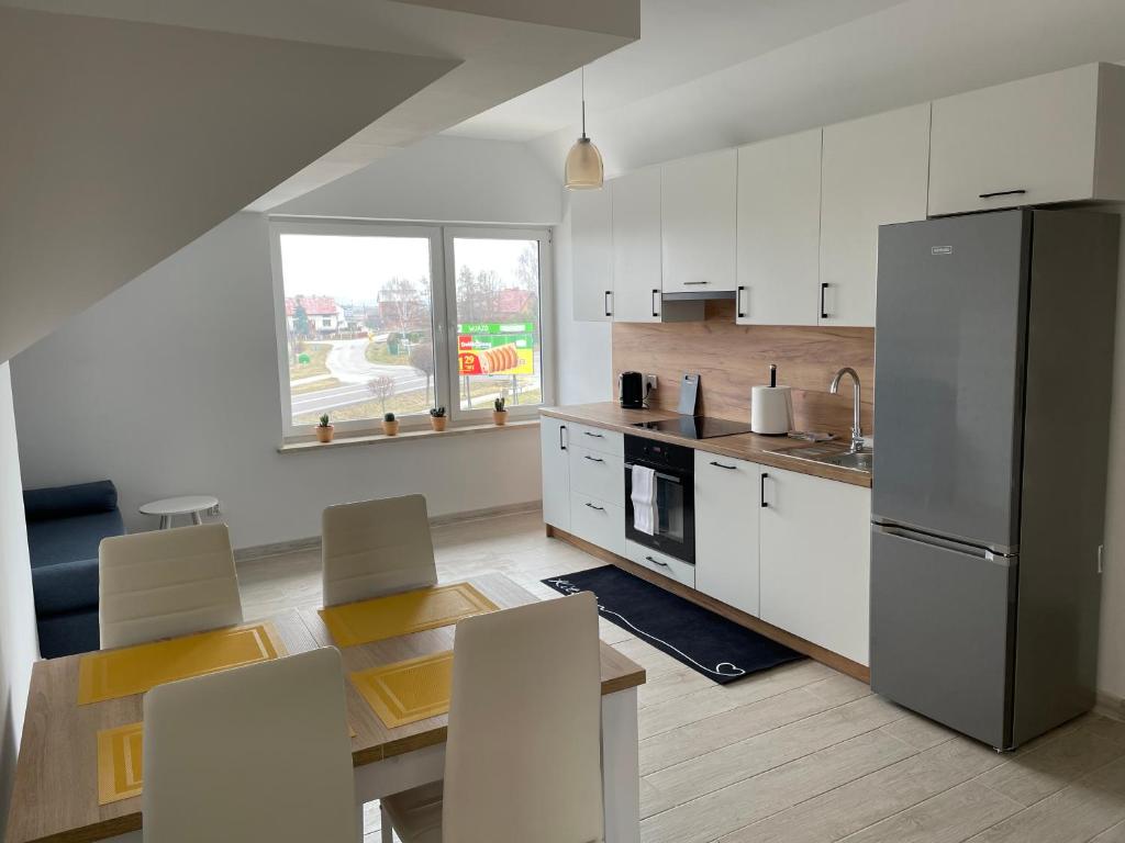 eine Küche mit weißen Schränken und einem Edelstahlkühlschrank in der Unterkunft Apartament Wierzawice in Wierzawice