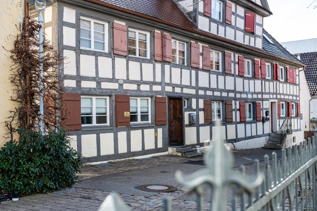 um edifício com portas brancas e vermelhas e uma cerca em FEWO Im alten Fachwerkhaus em Bad Buchau
