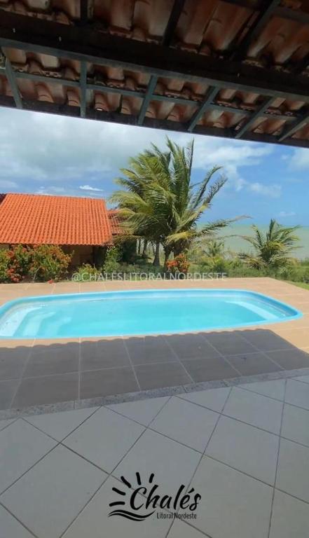 a large blue swimming pool in front of a house at Chalé com piscina privada vista mar-Zumbi-RN in Rio do Fogo