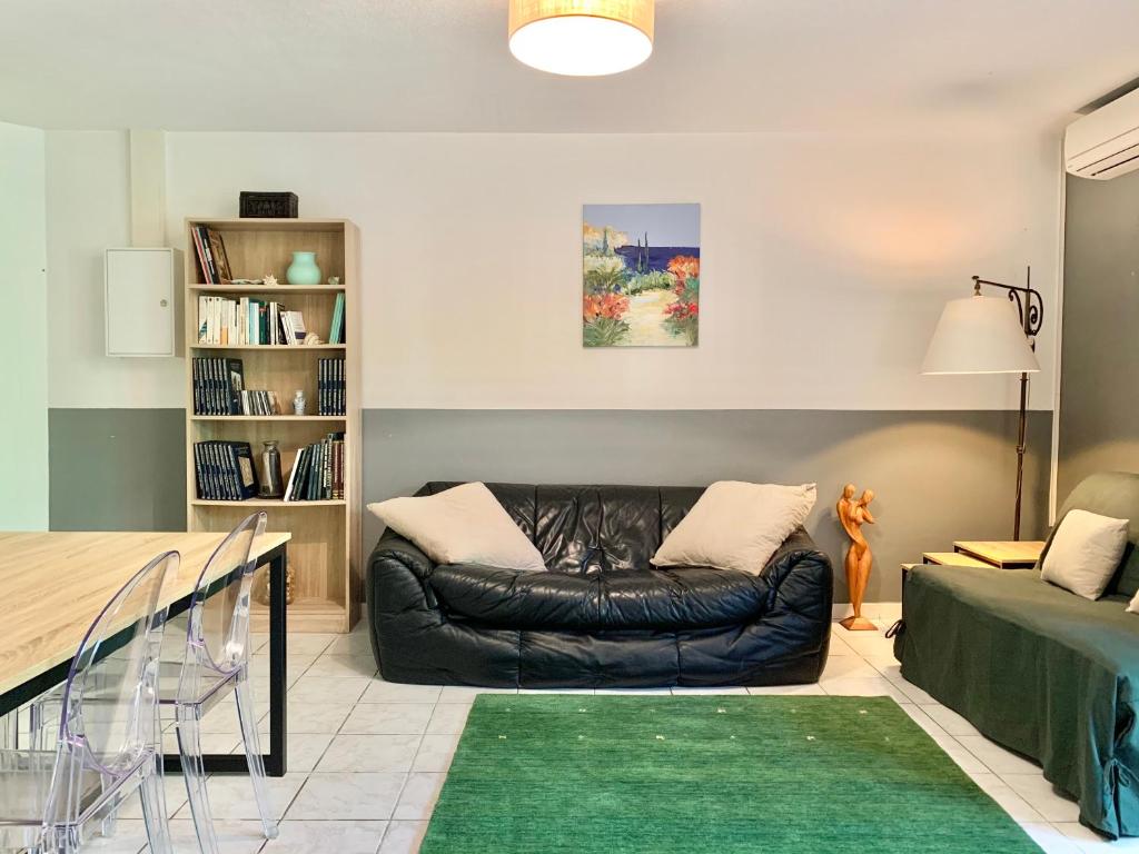 a living room with a leather couch and a table at Blagnac : appartement T2 avec jardin, parking et climatisation in Blagnac
