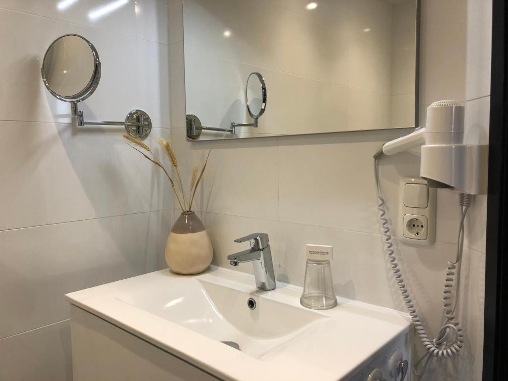 a bathroom with a sink with a mirror and a phone at Hotel Panta Rhei Cadzand-Bad in Cadzand