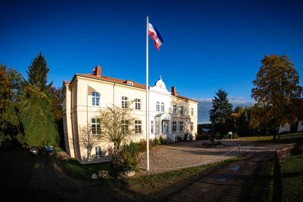 eine Flagge auf einer Stange vor einem weißen Gebäude in der Unterkunft Landhotel Schloss Daschow in Daschow