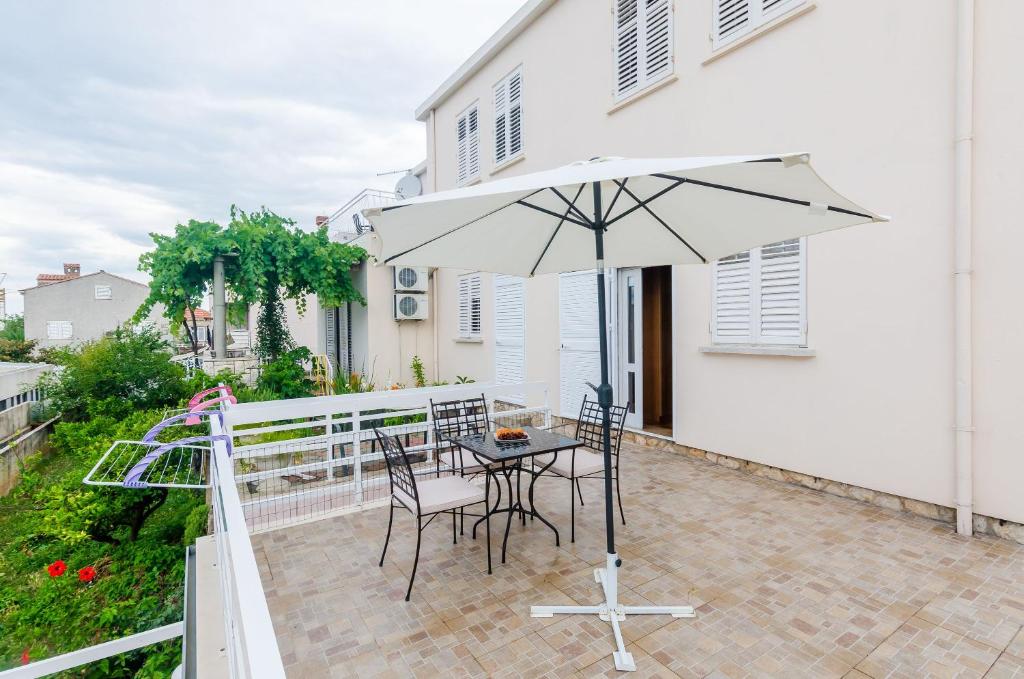 une terrasse avec une table, des chaises et un parasol dans l'établissement Villa Katarina, à Dubrovnik