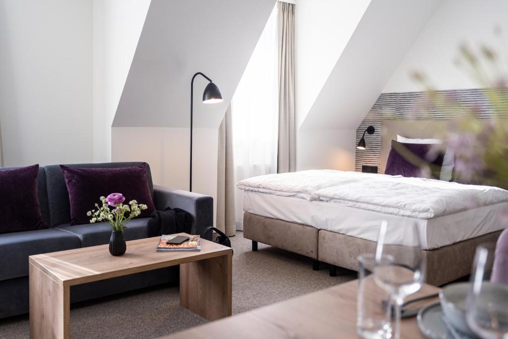 uma sala de estar com uma cama, um sofá e uma mesa em maakt Hotel em Stralsund