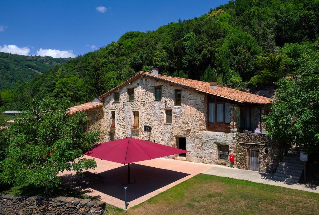 Casa Rural "Can Soler de Rocabruna" Camprodon في Rocabruna: منزل أمامه مظلة حمراء