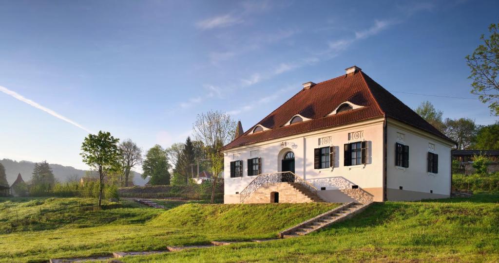 una pequeña casa blanca en una colina de hierba en Bethlen Estates Transylvania, en Daneş