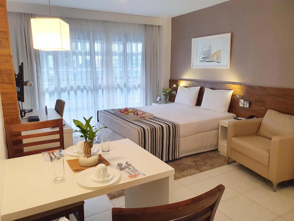 a hotel room with a bed, table and chairs at Fusion Hplus Express + in Brasília