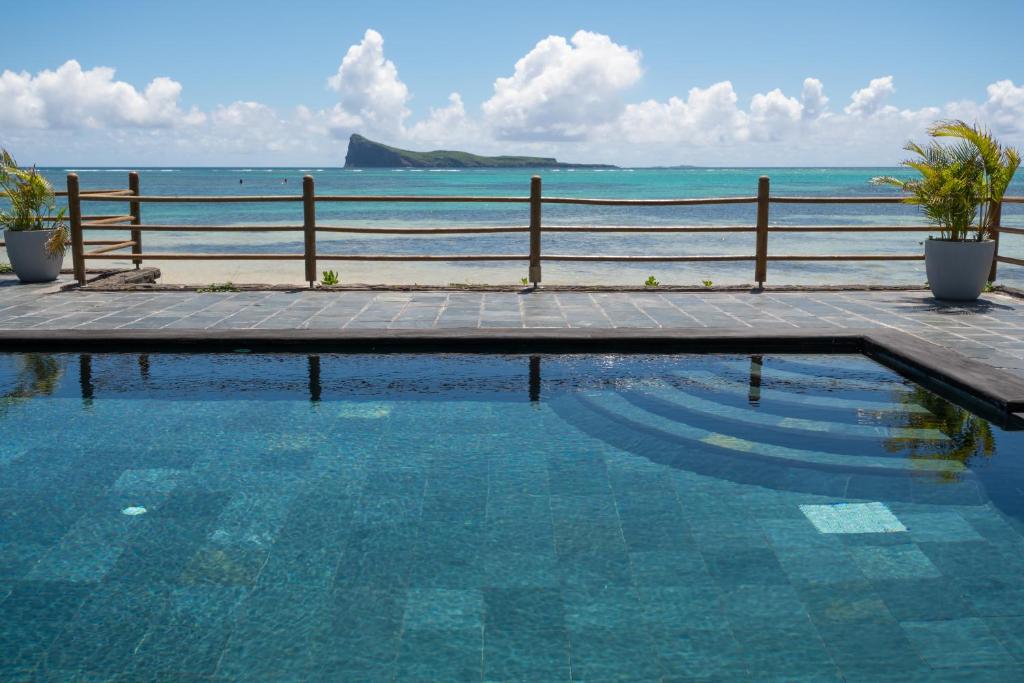 a swimming pool with the ocean in the background at Superbe appartement en bord de plage in Bain Boeuf