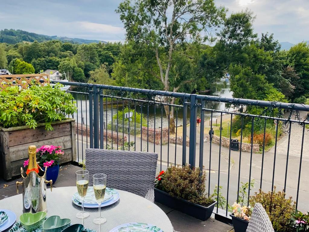 una mesa con copas de vino en la parte superior de un balcón en Riverside View Apartment in Balloch, Loch Lomond, en Balloch