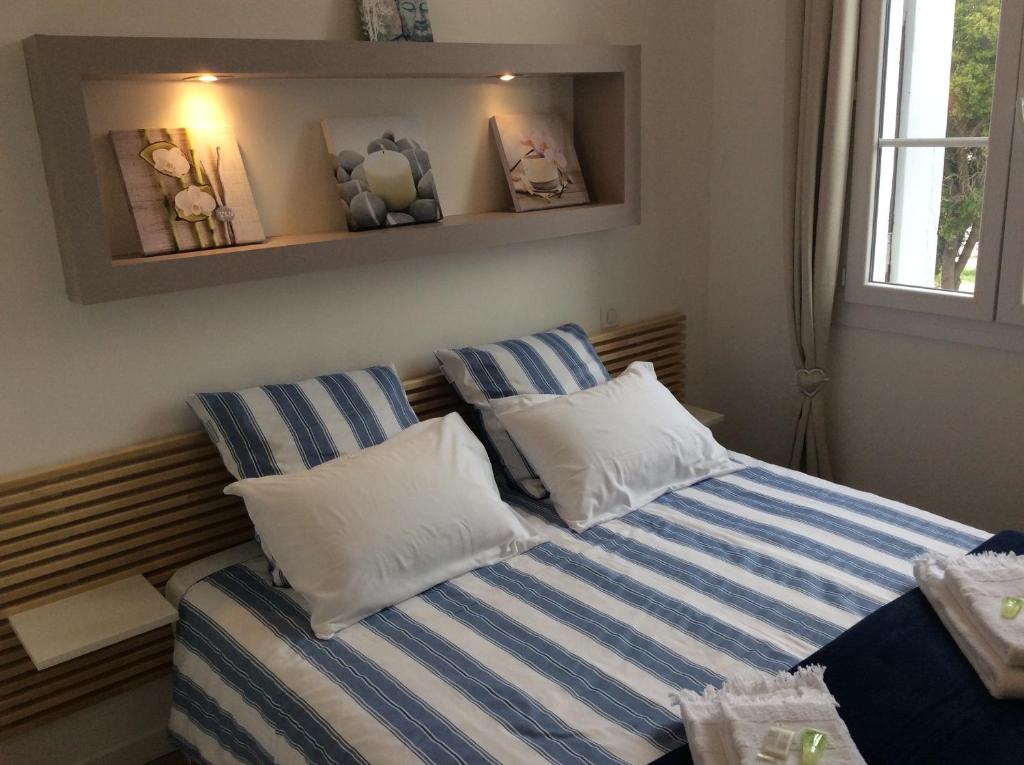 een slaapkamer met een bed met gestreepte lakens en een raam bij La Villa Soregia in Lattes