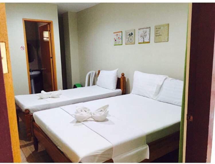 two beds with white bows on them in a room at Seascape Lodging House in Coron