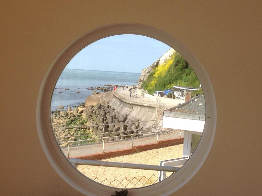 anorthole window with a view of a beach and the ocean at PORTHOLES in Ventnor