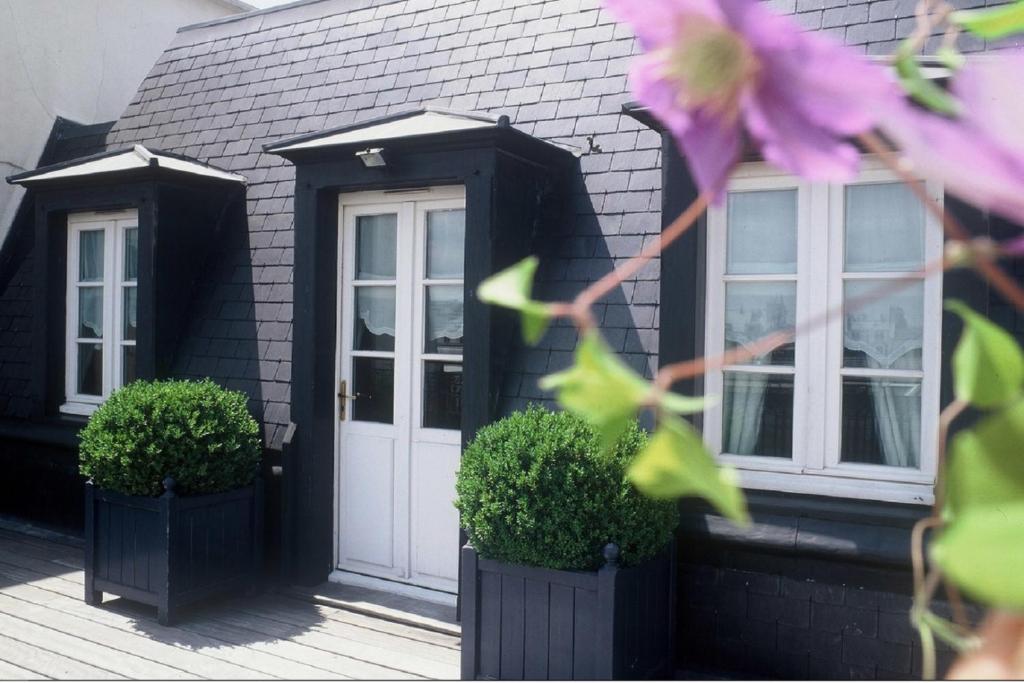 a black house with a white door and two plants at Golden Tulip Washington Opera in Paris