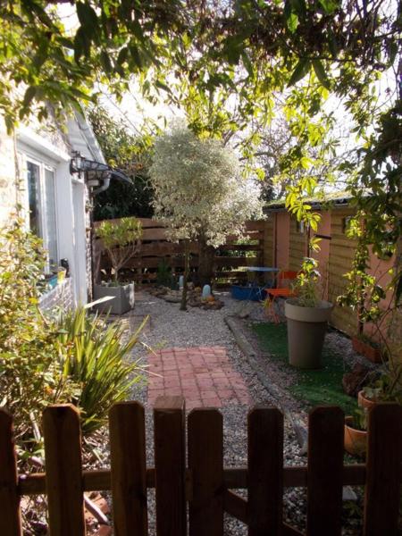 a backyard with a wooden fence and a brick walkway at Les deux moulins in Saint-Alban