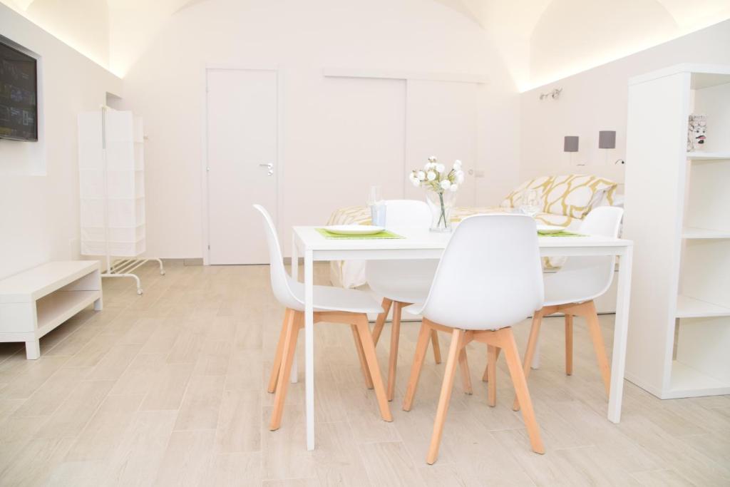 a white dining room with a white table and chairs at Casetta Verga Loft in Catania