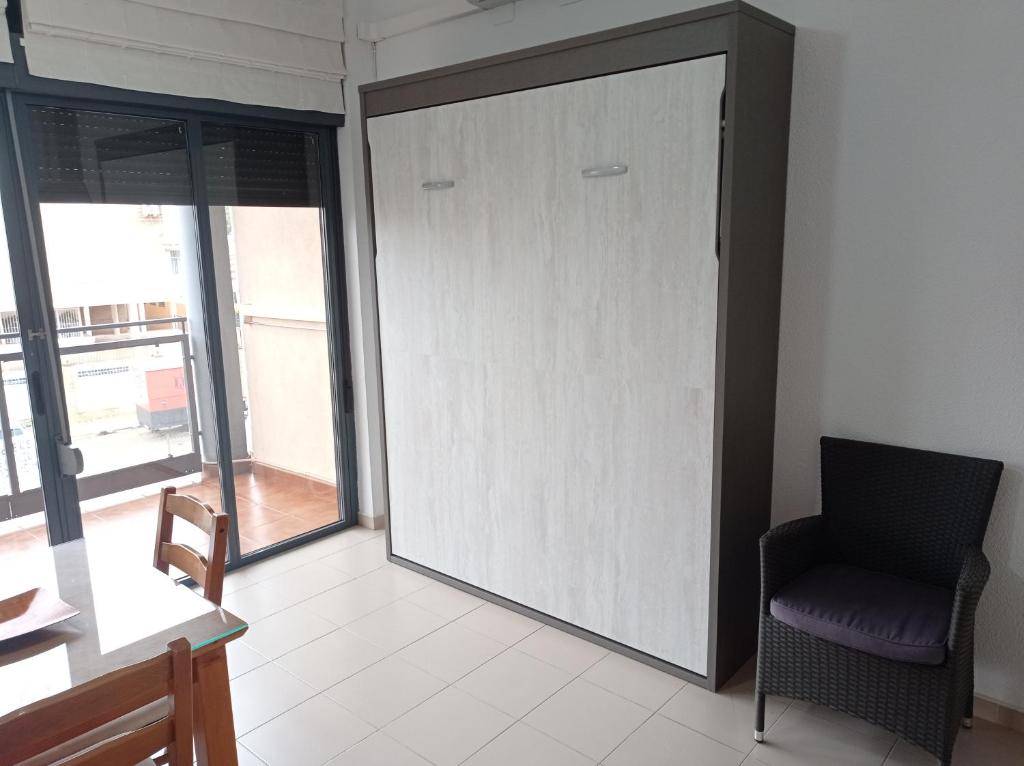 uma porta num quarto com uma cadeira e uma janela em ESTUDIO CON PISCINA Y GARAJE A 100 Mtr DE LA PLAYA em Isla Cristina