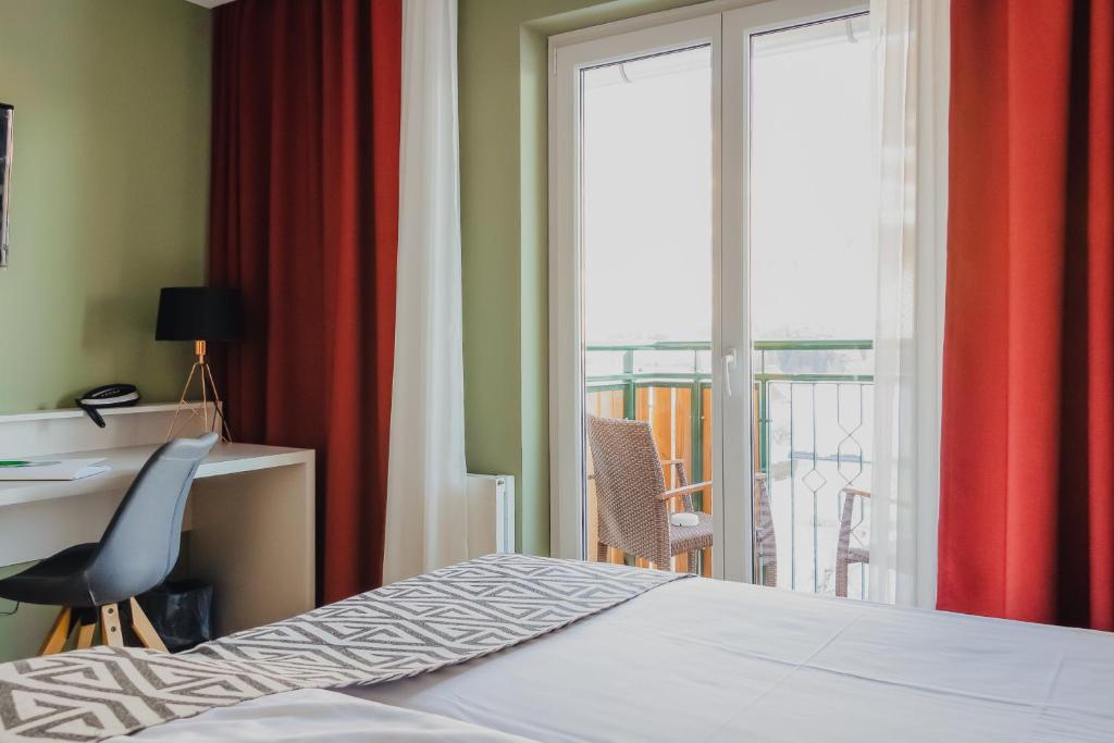 um quarto com uma cama, uma secretária e uma varanda em Hotel Alpenblick Kreischberg em St. Lorenzen ob Murau