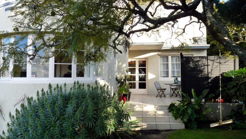 a white house with a table and chairs in a yard at Kiwi Heritage Homestay in Auckland