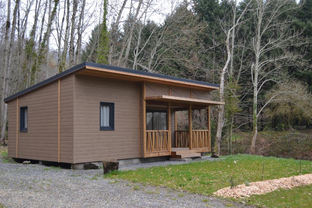 a small cabin with a porch in the woods at Chalets au bord de l'eau in Caudebronde