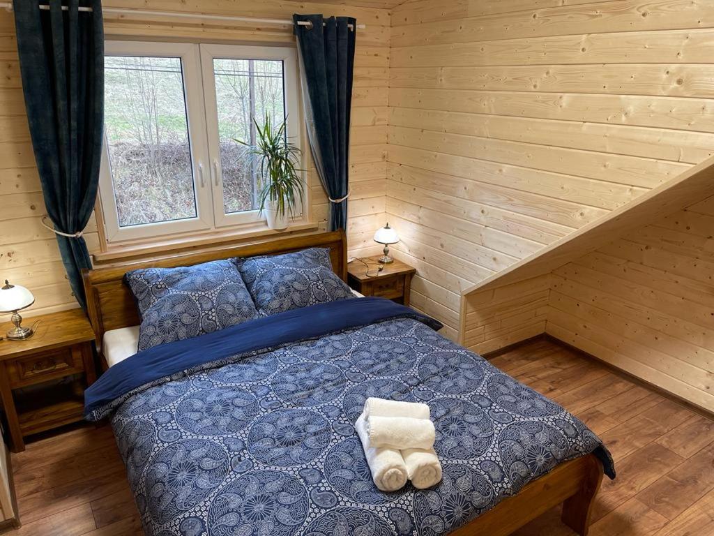 1 dormitorio con 1 cama azul y 2 toallas en Restauracja i Noclegi Izba Rybacka w Krainie Wygasłych Wulkanów en Podgórki