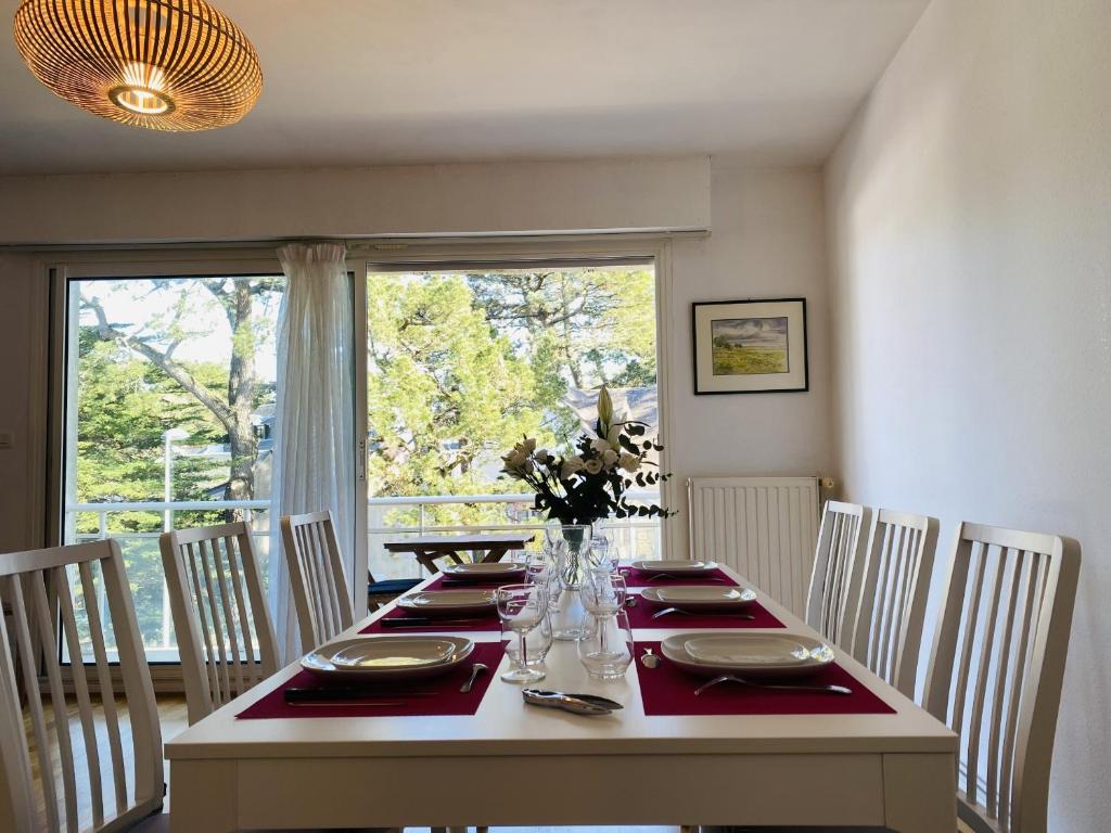d'une salle à manger avec une table, des chaises et une fenêtre. dans l'établissement MILN - Balcon, Parking privé, Plage 100m - T11, à Carnac