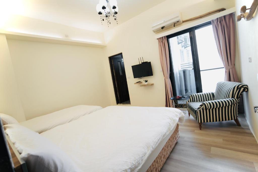 a hotel room with a bed and a chair at It's Mine Hostel in Taitung City