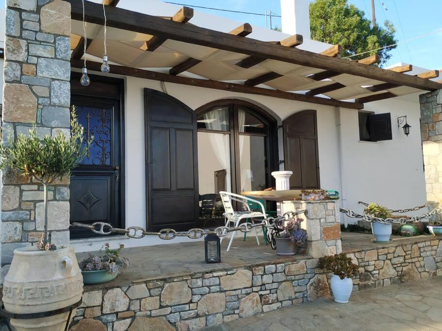 eine Terrasse mit einem Tisch und einer hölzernen Pergola in der Unterkunft ORFEAS HOYSE 1 in Patitiri