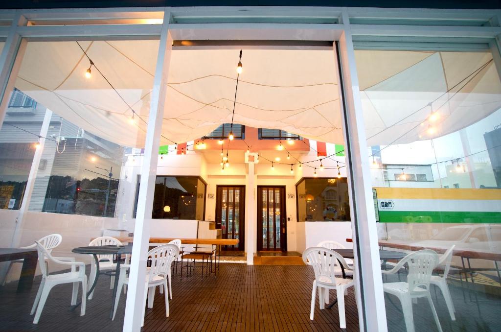 a restaurant with white chairs and tables and a glass door at It's Mine Hostel in Taitung City