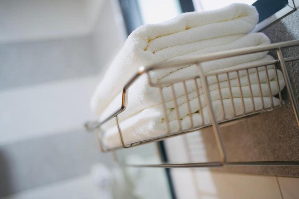 a towel rack with white towels on it at It's Mine Hostel in Taitung City