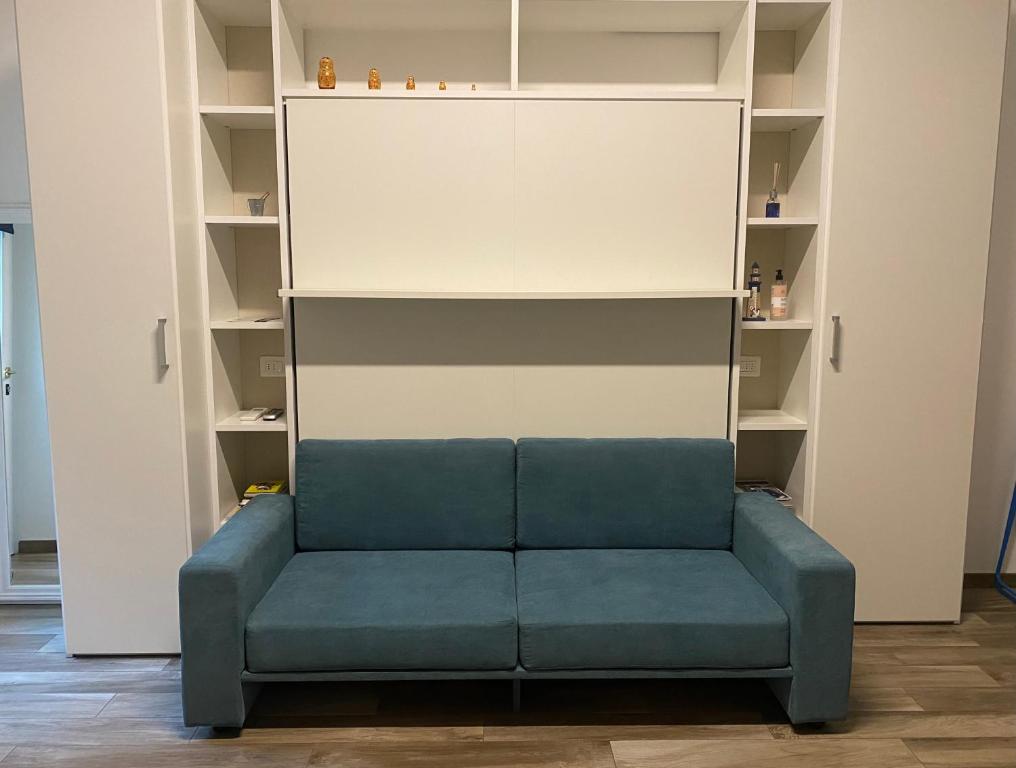 un sofá azul en una habitación con estanterías en Monolocale Agata, en Sestri Levante