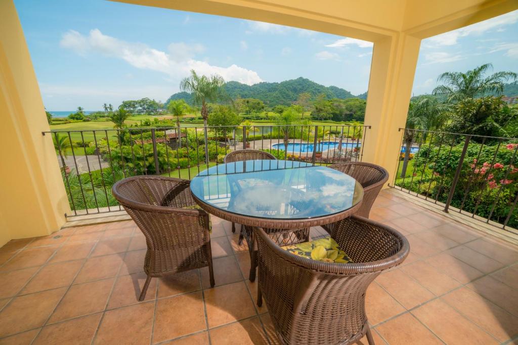 patio con mesa de cristal y sillas en el balcón en Los Suenos Resort Del Mar 3I by Stay in CR, en Herradura