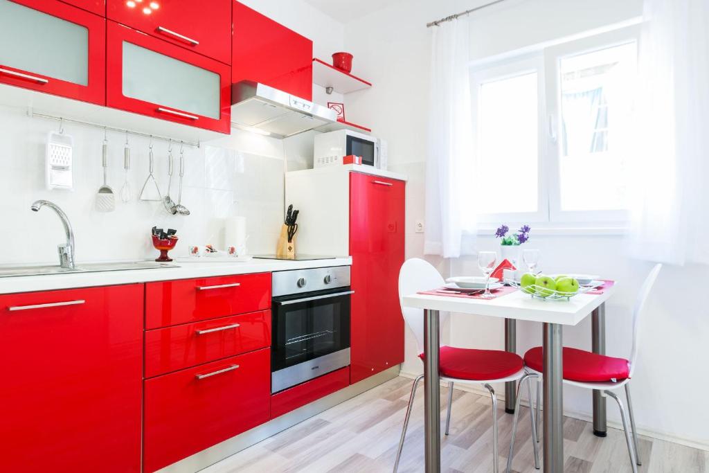 a red kitchen with a white table and red cabinets at Bagi apartment in old town center in Zadar