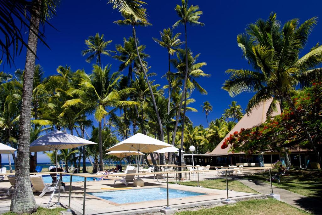 un complexe avec une piscine et des palmiers dans l'établissement Hotel Koulnoue Village, à Hienghène