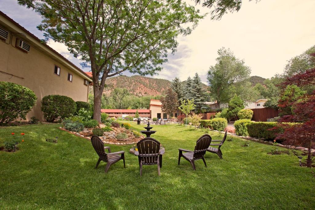 three chairs and a table in a yard at Glenwood Springs Cedar Lodge in Glenwood Springs
