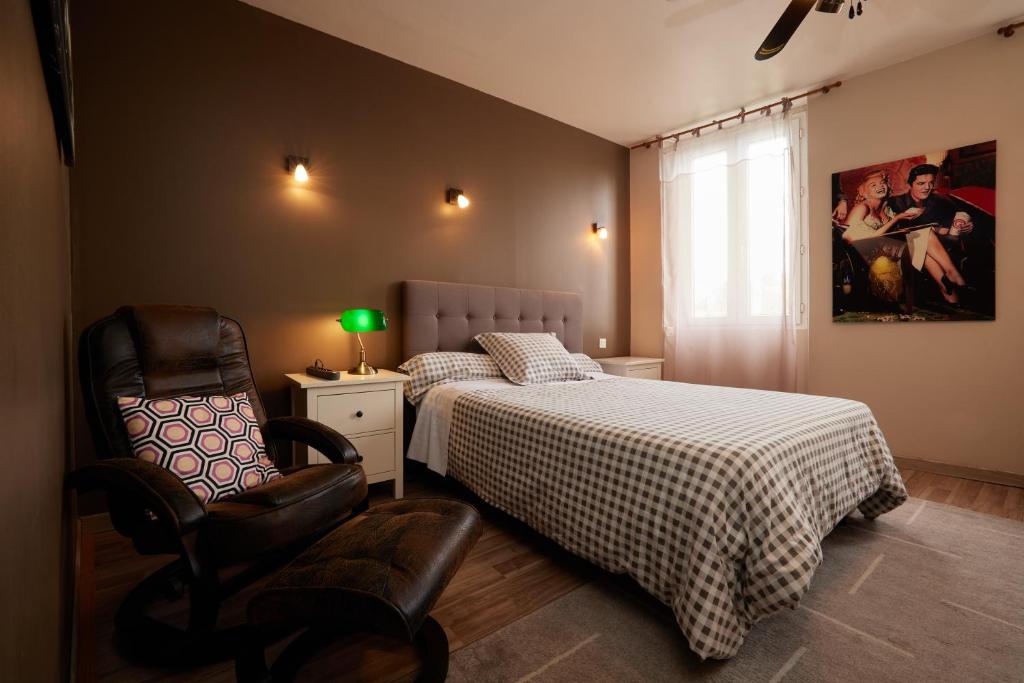 een slaapkamer met een bed en een stoel bij hotel de la paix in Pamiers