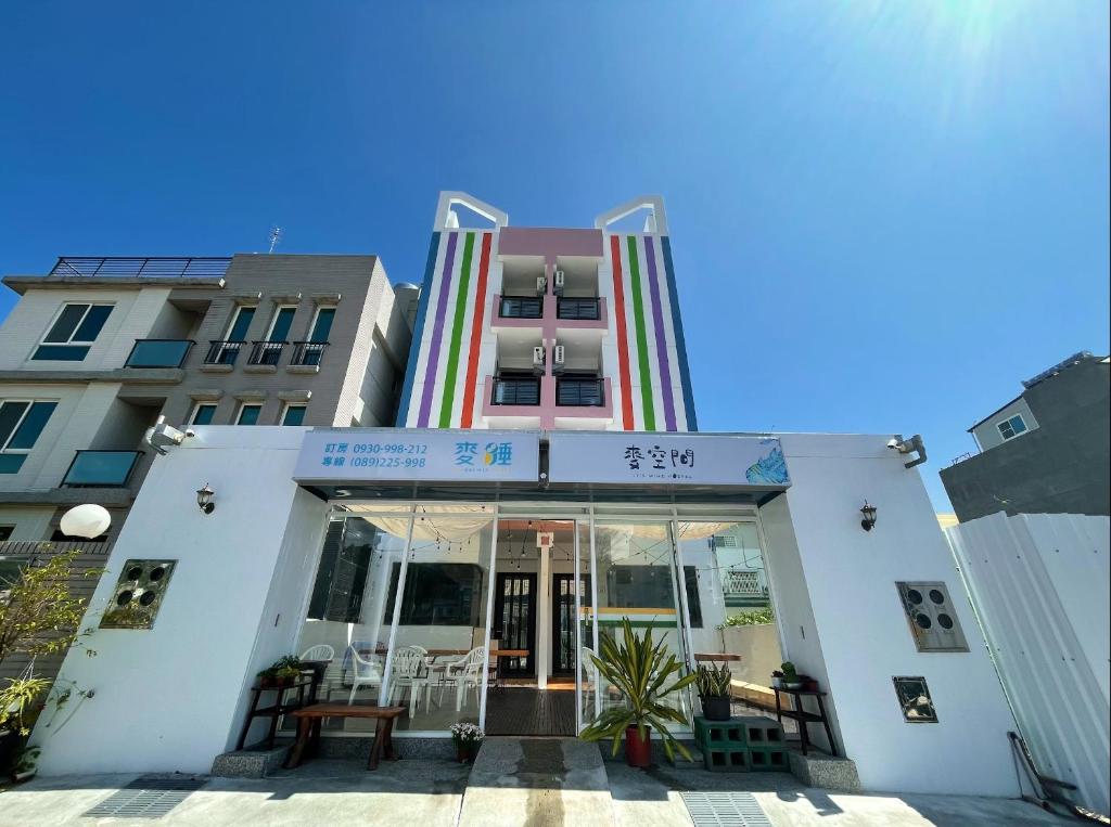 a building with glass doors and chairs in front of it at It's Mine Hostel in Taitung City