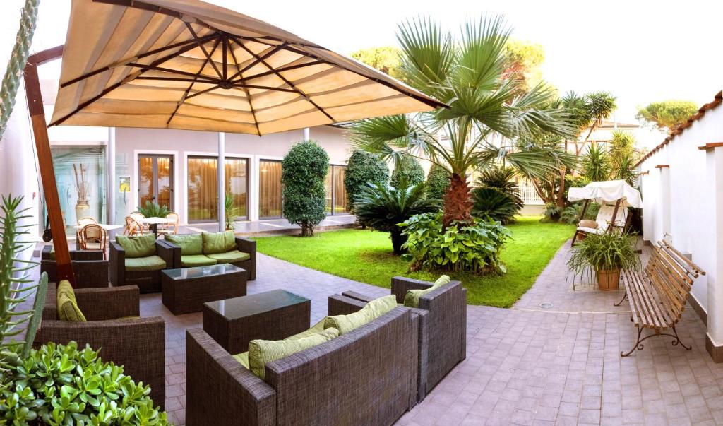 un patio con muebles y una sombrilla grande en Hotel Spinelli en Viareggio