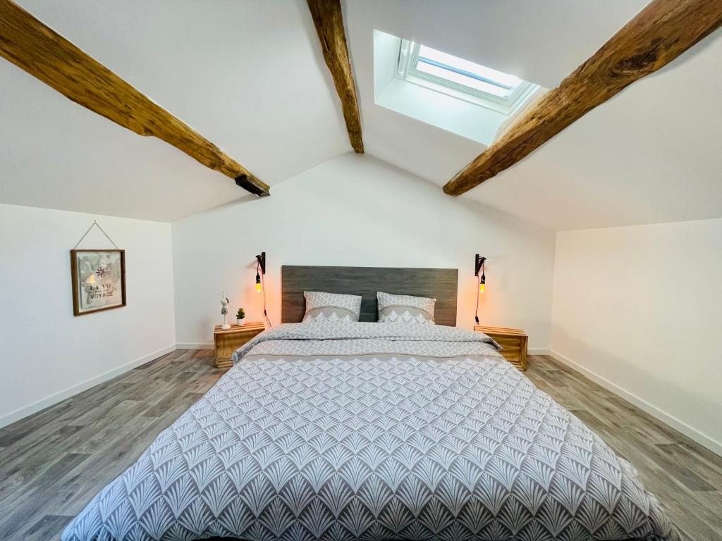 a bedroom with a large bed with wooden beams at La Carrée des Amis in Lusignan