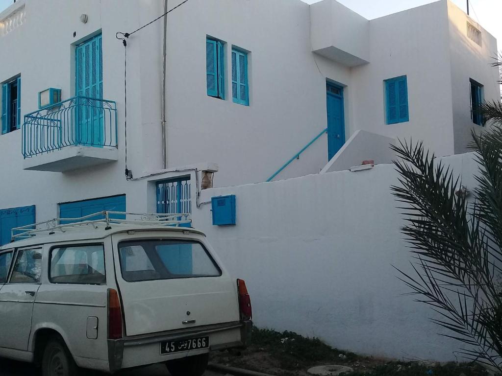 un coche blanco estacionado frente a un edificio en Dar Essadeg en Tataouine